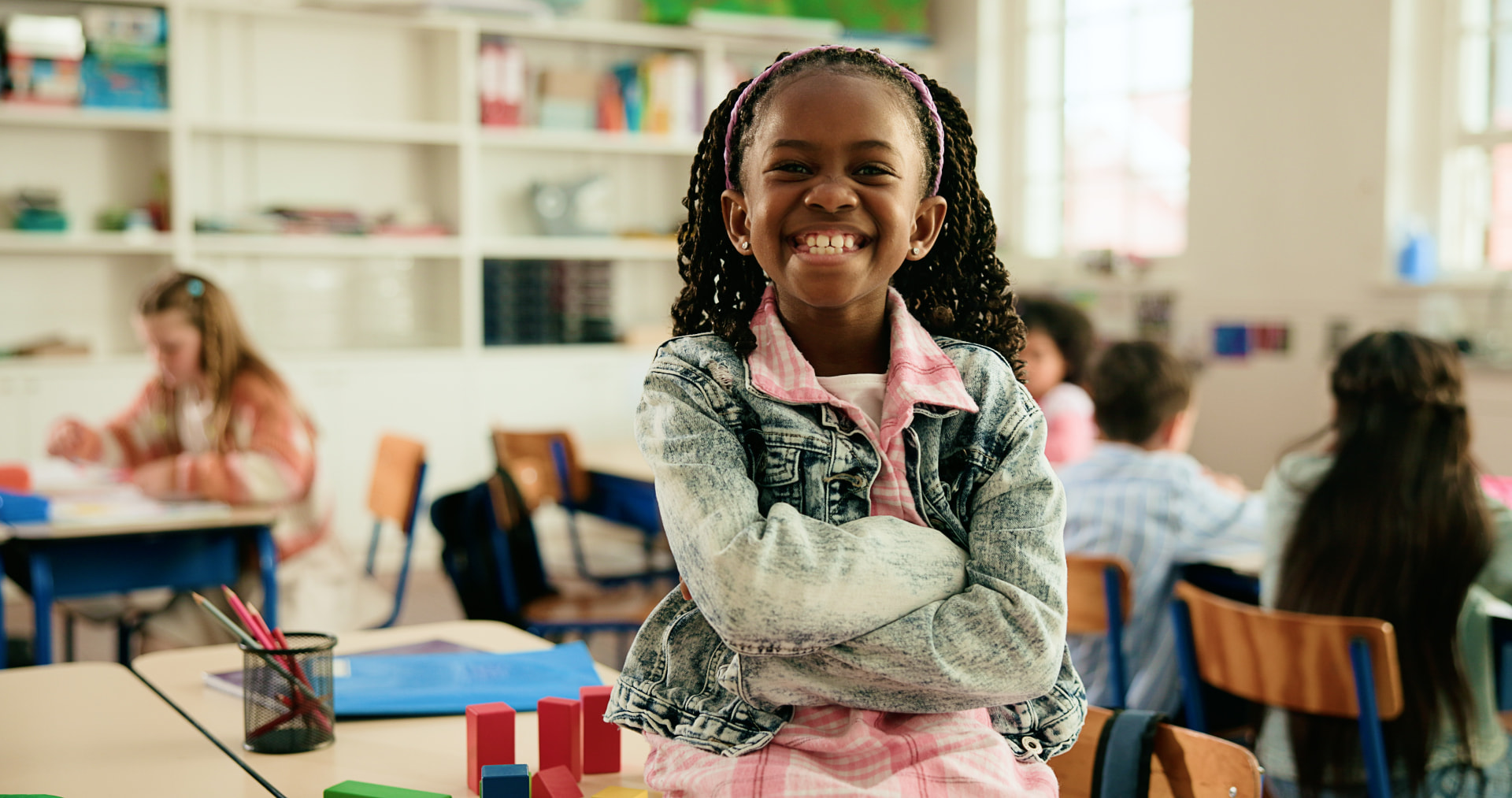 Illustrative photo of a smiling elementary-age girl in a classroom
